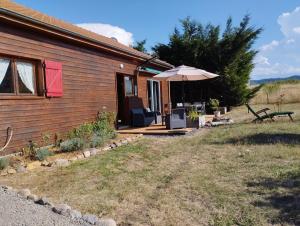 a wooden cabin with an umbrella and chairs on the porch at Chalet Les Adrets du Sancy in Saint-Diéry