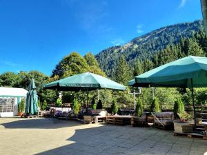 eine Terrasse mit Sonnenschirmen, Stühlen und Tischen mit Bergen in der Unterkunft Berghotel Almagmach in Immenstadt im Allgäu
