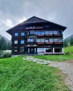 a large building with a gambrel roof on a grass field at Berghotel Almagmach in Immenstadt im Allgäu