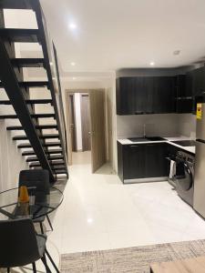 cocina con mesa de cristal y escalera en Royal Luxury Apt at Embassy Garden, en Accra