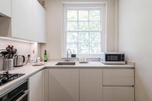 a white kitchen with a sink and a microwave at Stylish Kings Cross Flat in London