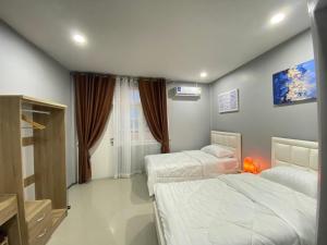 Un dormitorio con dos camas y una ventana. en คาเฟ่ เดอ แจ่วบอง รูมแอนด์เซอร์วิส, en Khon Kaen