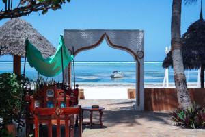 een boog op het strand met een boot in het water bij Zanzibar House Boutique Hotel in Matemwe