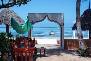 Zanzibar House Boutique Hotel في ماتيموي: قوس على الشاطئ مع قارب في الماء