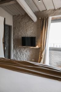 a room with a tv on a stone wall at Bnb Verdeolivo in Coriano