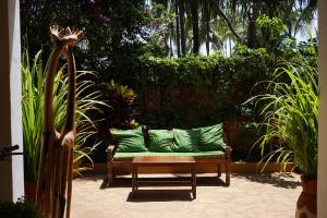 a bench with green pillows in a garden at Zanzibar House Boutique Hotel in Matemwe