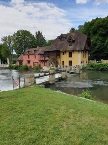 a house with a thatched roof on a bridge over a river at l'escapade in Gasny