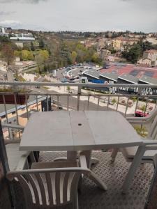 una mesa de picnic en un balcón con vistas a la ciudad en Appartement 4 chambres, 5 lits et un canapé convertible en Annonay