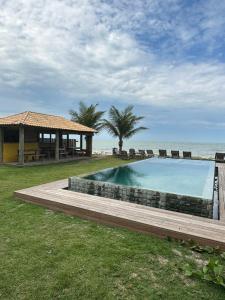 a swimming pool next to a beach with a house at Tamikuã Mar Pousada in Caraíva