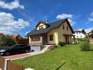 a house with a car parked in the driveway at Apartmán u Kovářů in Kašperské Hory