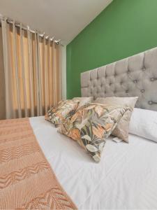 a bed with two pillows and a green wall at Peaceful & Modern Apartment in Cartagena de Indias