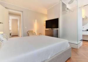ein weißes Schlafzimmer mit einem großen Bett und einem TV in der Unterkunft Livin' Portofino GOLD in Santa Margherita Ligure