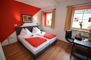 Schlafzimmer mit einem Bett mit roten Wänden und einem Schreibtisch in der Unterkunft Hotel Traube in Zell am See