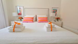 a white bed with towels and orange bows on it at Casa "Vô Lando" - Nazaré - Alojamento Local in Nazaré +41 photos