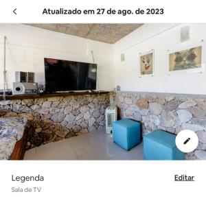 a living room with a tv on a stone wall at Vista Espetacular em Angra dos Reis in Angra dos Reis