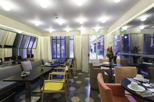 a restaurant with tables and chairs and windows at Hotel Saint Dominique in Paris