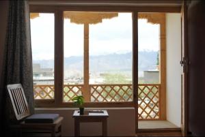 a room with a window with a chair and a table at gultuk home stay in Leh
