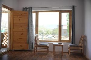 レーにあるgultuk home stayのテーブルと椅子、窓が備わる客室です。