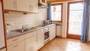 cocina con armarios blancos, fregadero y ventana en Pretzerhof, en Campo di Trens