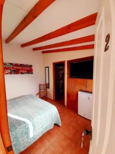 1 dormitorio con 1 cama y TV de pantalla plana en Cabañas Garcia, en Algarrobo