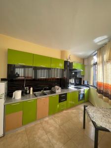 uma grande cozinha com armários verdes e uma mesa em Door Number 3 em Tirana
