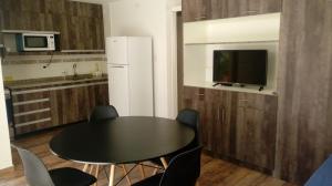 a kitchen with a black table and a white refrigerator at Abril Dptos Temporarios in San Juan