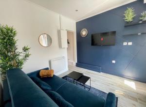 ein Wohnzimmer mit einem blauen Sofa und einem TV in der Unterkunft L’oasis urbaine - Charmant studio proche de Paris in Alfortville