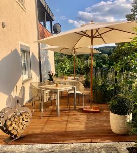 um deque de madeira com uma mesa e um guarda-chuva em Tier- & kinderfreundliches Ferienhaus - KEINE MONTEURE em Priesendorf