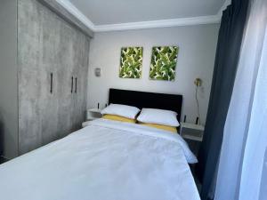 a bedroom with a large white bed with two windows at Ivywood loft @ Monarch Studios in Polokwane