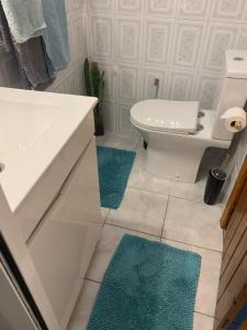 un bagno con un water bianco e tappeti blu di Waves Song - Cottage a Porto Moniz Altre 21 foto