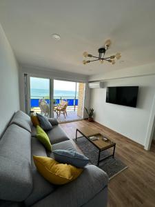 Sala de estar con sofá gris y vistas al océano en ¡Precioso ático frente al mar! en Denia