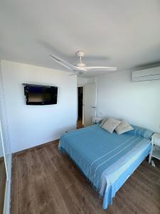 1 dormitorio con 1 cama azul y TV de pantalla plana en ¡Precioso ático frente al mar! en Denia