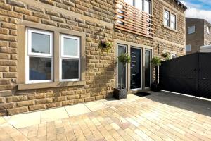 uma casa de tijolos com duas janelas e um portão preto em *RA7C* For your most relaxed & Cosy stay + Free Parking + Free Fast WiFi * em Batley