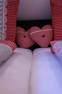 - deux cœurs sur un lit avec des oreillers rouges et blancs dans l'établissement Renatas Ferienwohnung Sasbachwalden, à Sasbachwalden