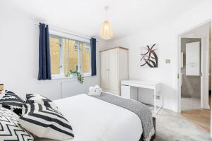 een witte slaapkamer met een bed en een bureau bij 3-bed apartment in Limehouse in Londen