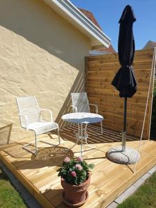 un patio con 2 sillas, una mesa y una sombrilla en Stad och strand i Höganäs en Höganäs