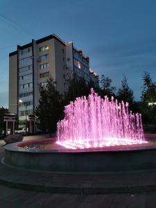 a pink water fountain in front of a building at 1 комнатная квартира в самом центре с видом на сквер in Kostanay