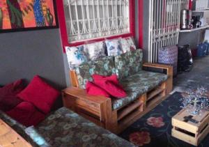 sala de estar con sofá y almohadas rojas en "LE CHAT QUI PECHE" Hostel a 150 metros da PRAIA de PAJUCARA, en Maceió
