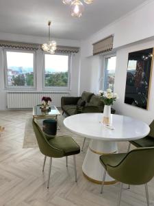 a living room with a white table and green chairs at Elite Apartment in Sibiu