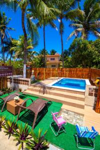 a swimming pool with two lawn chairs and a table and chairs at Antunes vila maragogi in Maragogi