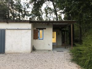 un petit bâtiment blanc avec une porte bleue et des arbres dans l'établissement Gite de la fontaine Bondrée, à Vernou-sur-Brenne