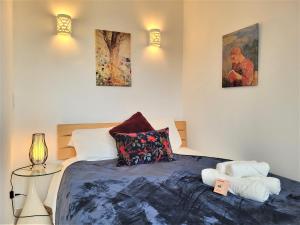a bedroom with a bed and two paintings on the wall at Le Prasino - Paisible appartement proche RER in Massy
