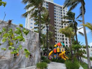 um parque infantil em frente a um edifício com palmeiras em Salinas Premium Resort Ap 1 QT em Salinópolis
