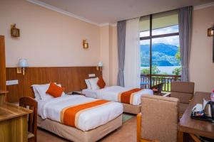 Una habitación de hotel con dos camas y balcón. en Hotel Fewa Camp, en Pokhara