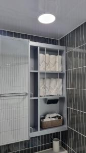 un bagno con asciugamani bianchi su scaffali in una stanza di Mia House a Daegu