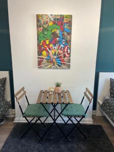 a table and two chairs with a painting on the wall at Willesden Green ROOMS in London