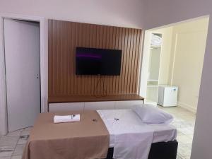 um quarto com uma cama e uma televisão de ecrã plano em Pousada Sol da Enseada Guarujá no Guarujá
