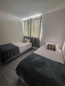 two beds in a small room with a window at Peaceful & Modern Apartment in Cartagena de Indias