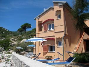 a house with chairs and umbrellas in front of it at Onda Su Onda Appartamenti in Seccheto