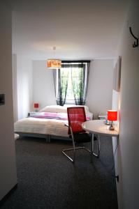 a bedroom with a bed and a red chair and a table at Hotel Restauracja Venus in Moderówka +31 photos